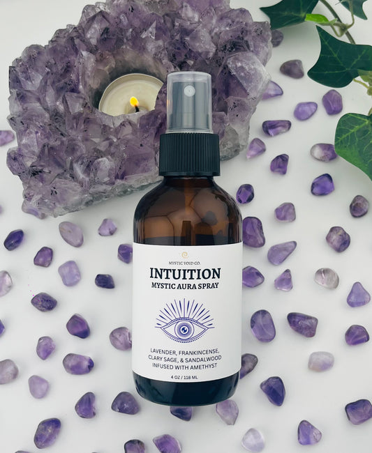 Mystic Aura Spray bottle labeled 'Intuition' surrounded by purple crystals and amethyst rock on a white background.